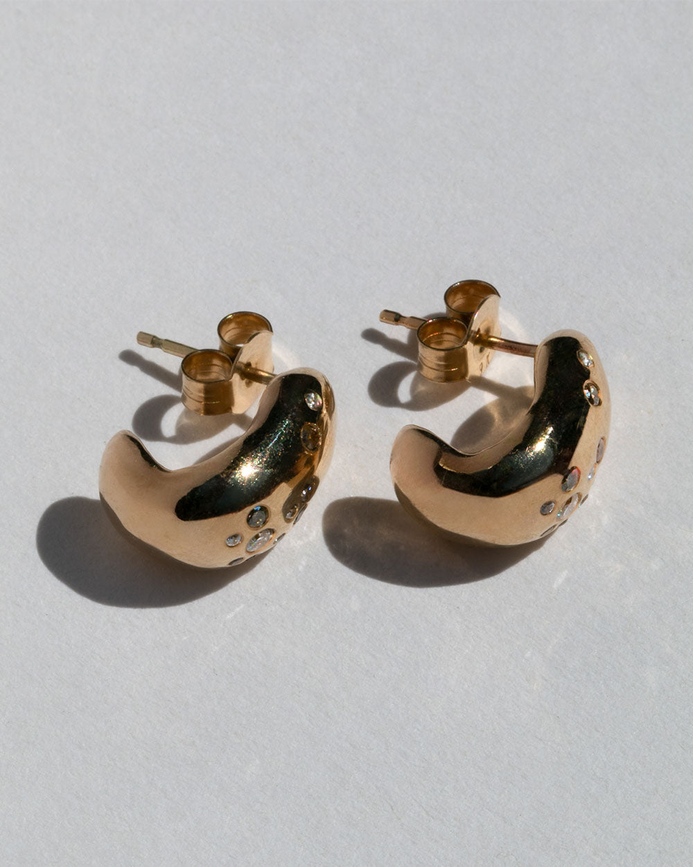 9ct solid yellow gold hoop earrings with flush set champagne, grey and white diamonds on white background.
