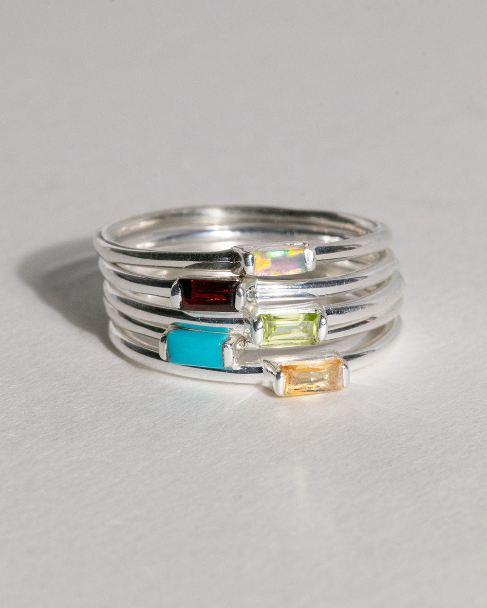 stack of birthstone rings including August Peridot Birthstone Baguette Ring