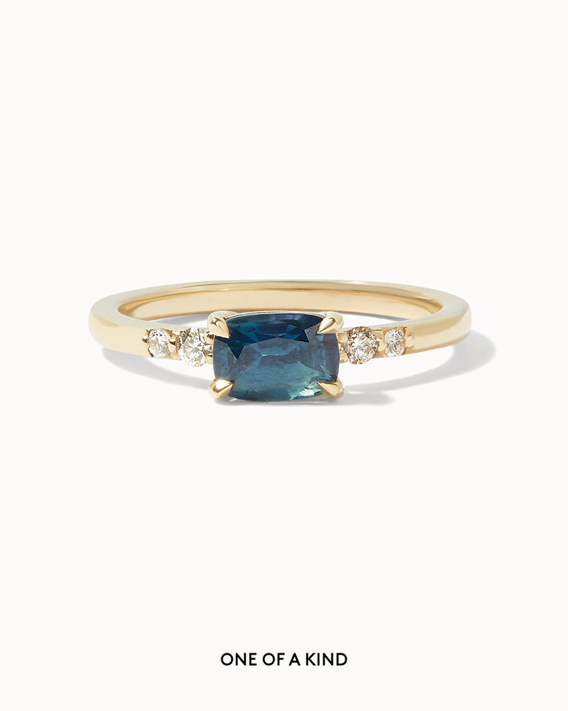 Solid gold engagement ring featuring an oval blue Sapphire and four round cut white diamonds on the sides handcrafted in London by Maya Magal London