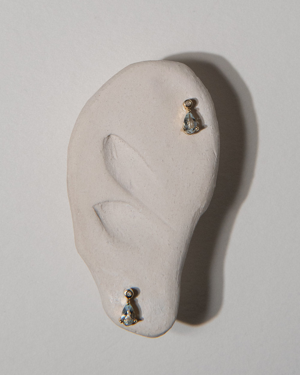 Aquamarine and Diamond Pear Drop Earrings 9 ct gold displayed on ceramic
