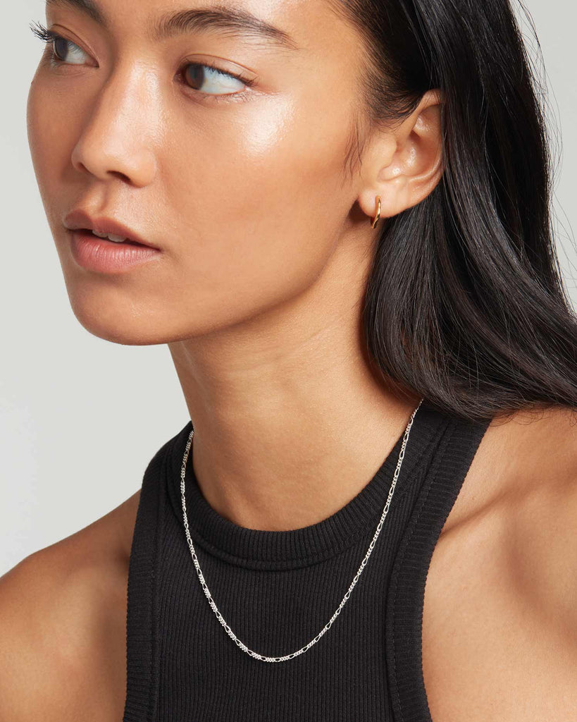 Model wears sterling silver figaro chain necklace by Maya Magal