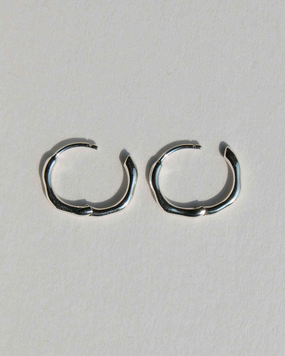 Side view of A pair of sterling silver hoop earrings with an organic texture. 925 recycled sterling silver. Side view with closure closed.