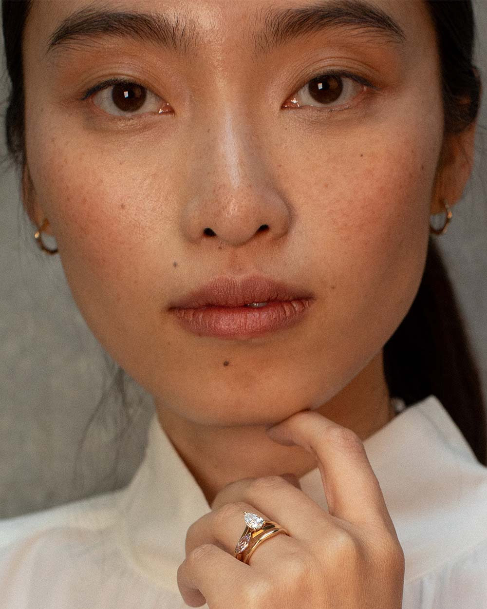 Front view of model wearing 9ct solid gold huggie organic hoop earrings side view on a white background.