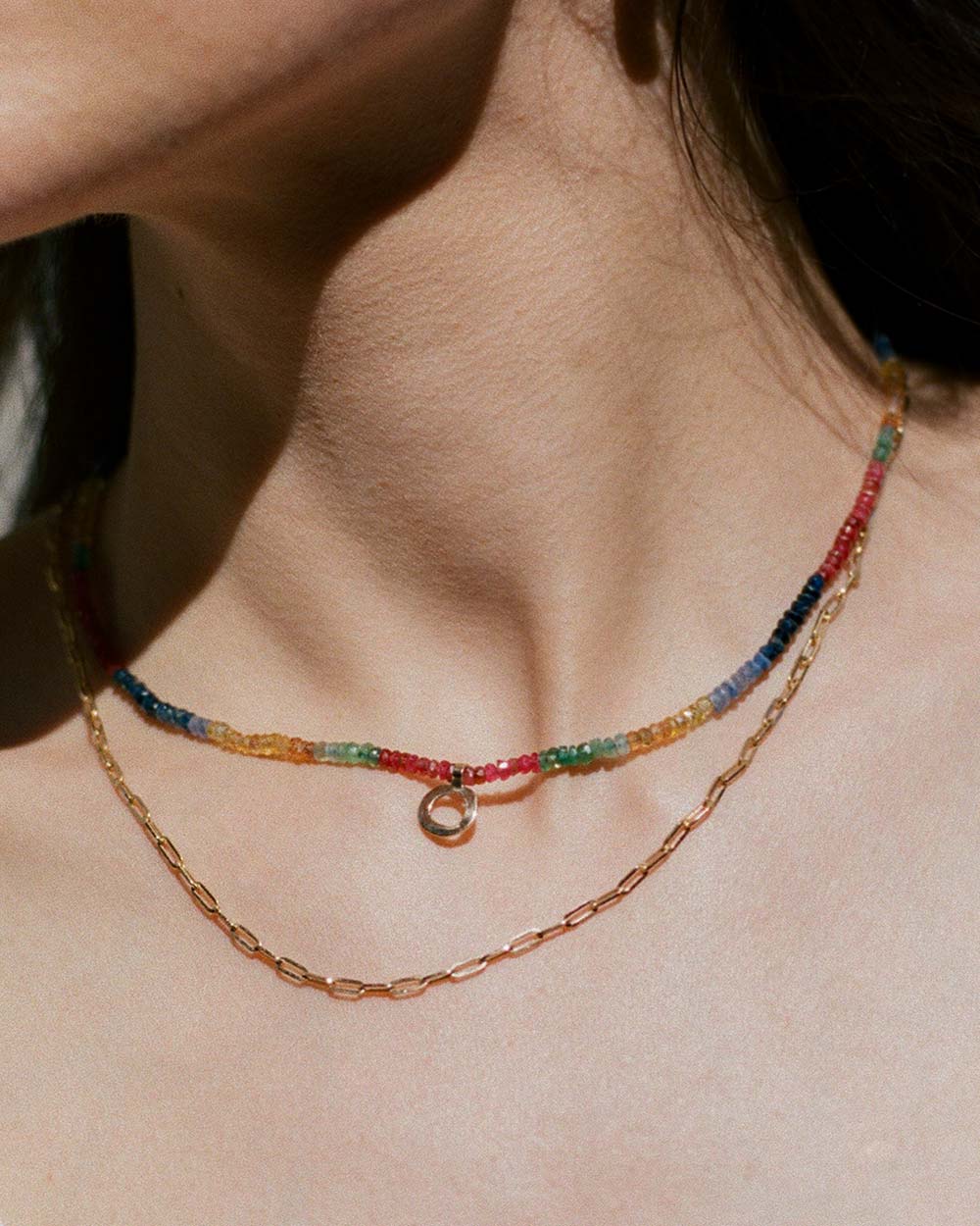 sapphires, emeralds and rubies beaded necklace handstrung on silk thread handcrafted in London with 9ct solid gold organic charm by Maya Magal London