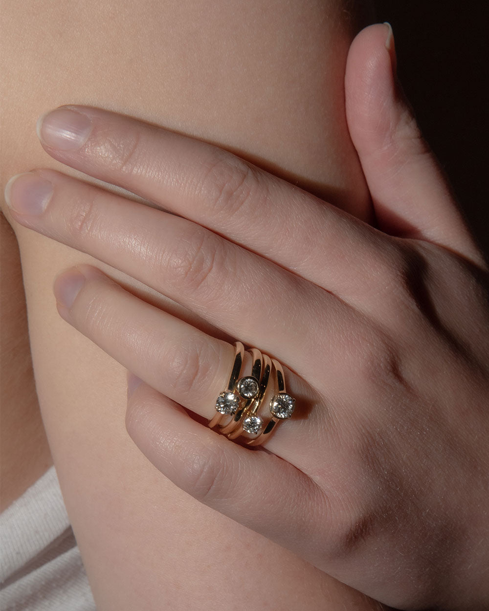 model wearing a stack of rings including 0.5ct Lab Grown Diamond Halo Ring with 9 Ct solid gold band
