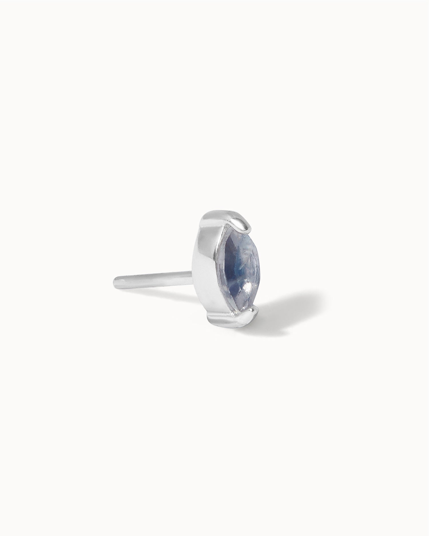 Side view of labradorite solid white gold stud on white backdrop.