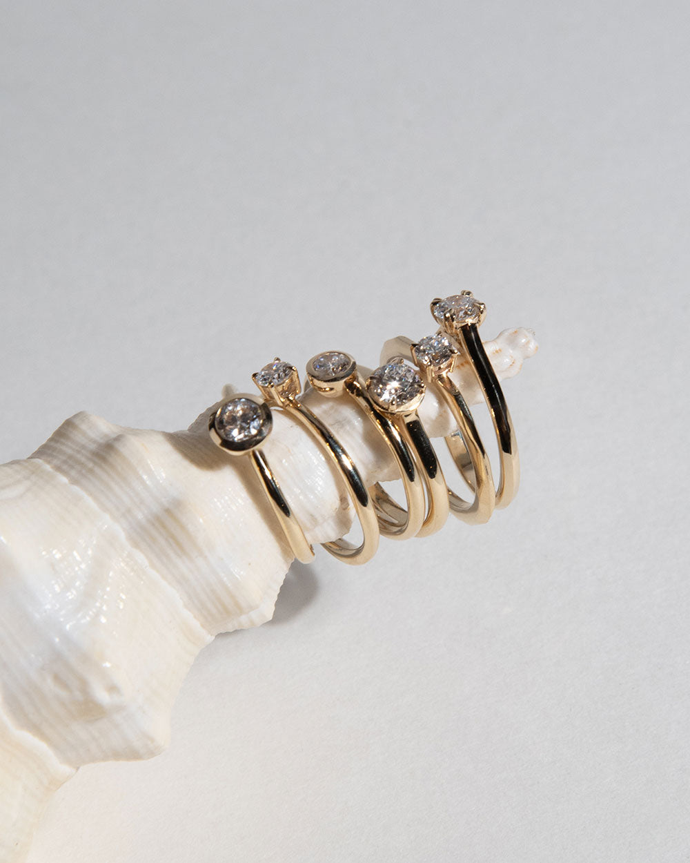 display of gold rings on sea shell including 0.5ct Lab Grown Diamond Bezel Ring with 9 Ct solid gold band