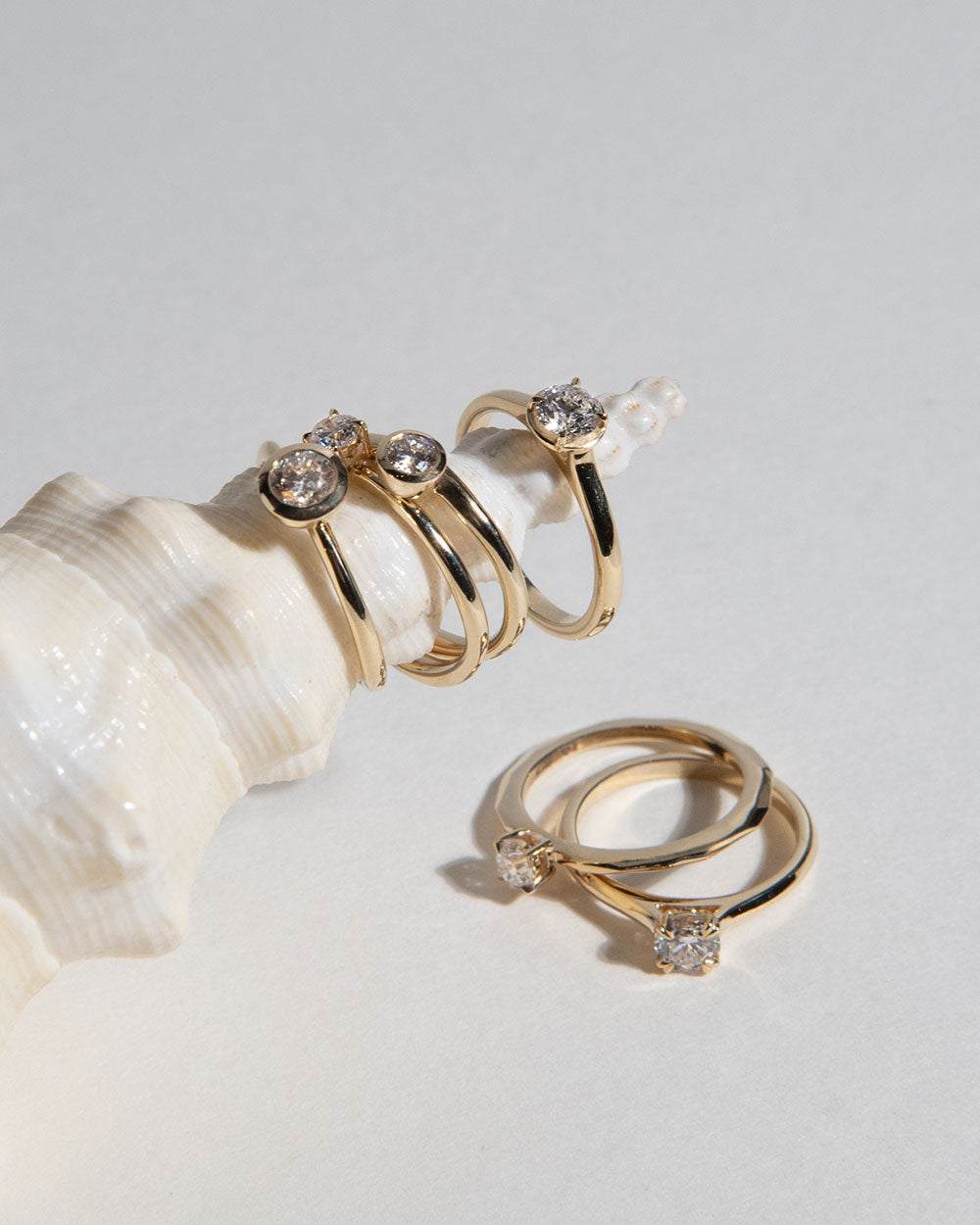 display of gold rings on sea shell including 0.5ct Lab Grown Diamond Halo Ring with 9 Ct solid gold band