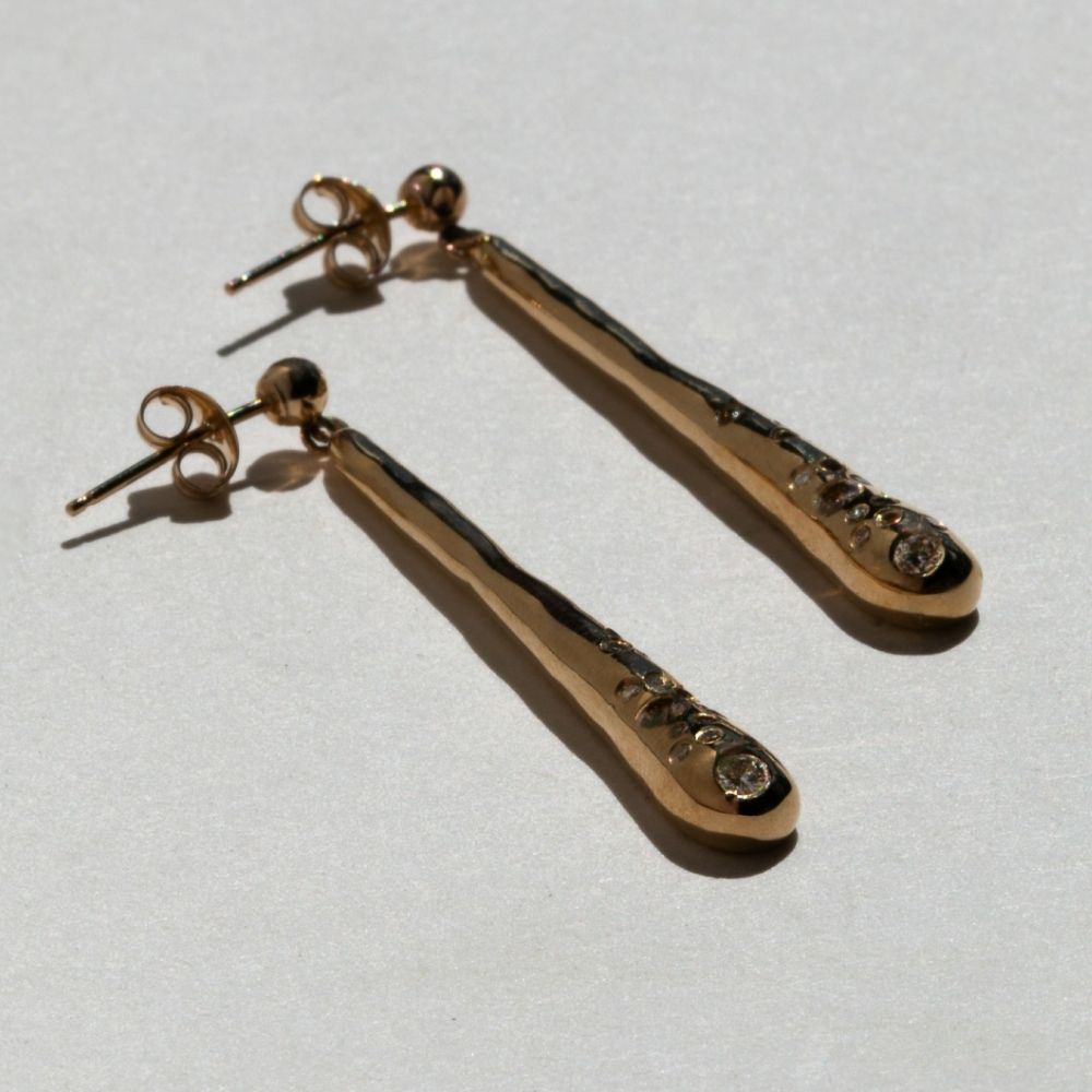A pair of solid gold drop earrings set with champagne diamonds by Maya Magal London
