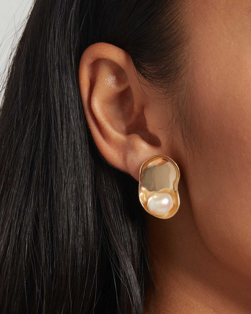 Model wears Baroque pearl disc earrings handcrafted with solid gold in London by Maya Magal
