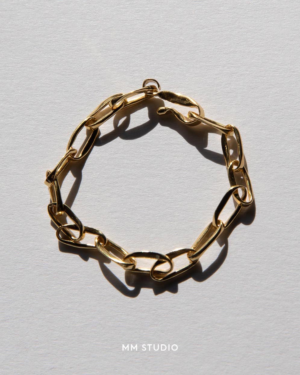 Gold chain bracelet on a light gray background with 'MM Studio' branding.