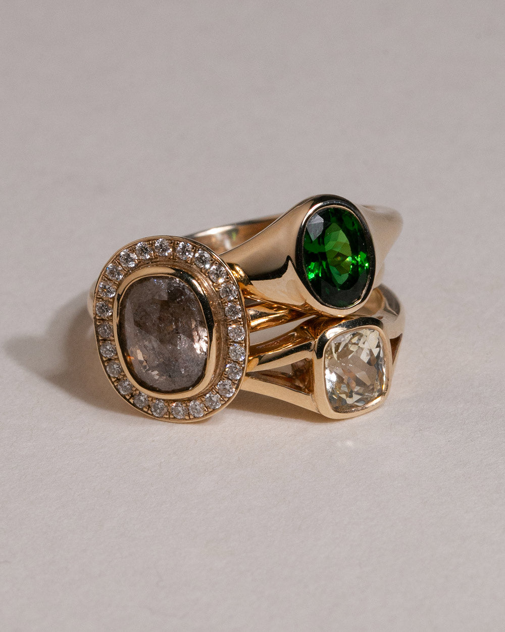 9ct gold Ring with 0.78ct oval-cut Tanzanian green tourmaline, chosen for its rich, vibrant colour and natural character. Flush-set signet design on a white background.displayed with 2 other gold rings. 