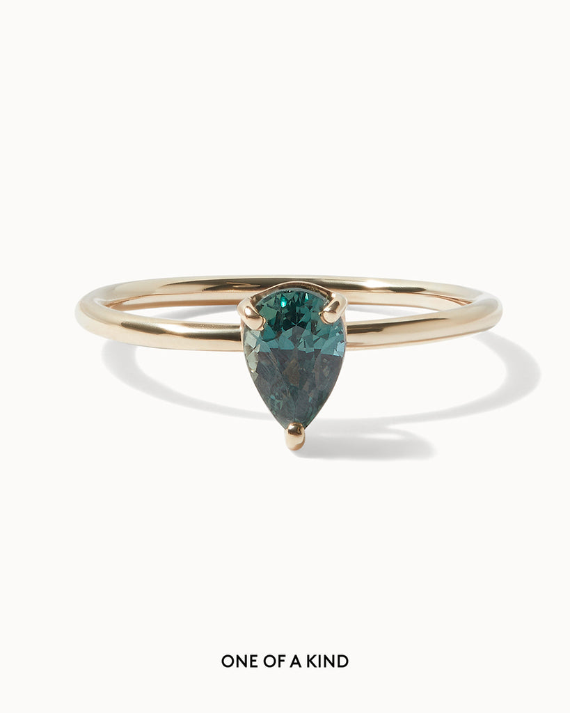 Solid gold solitaire engagement ring featuring a pear cut teal sapphire handcrafted in London by Maya Magal London