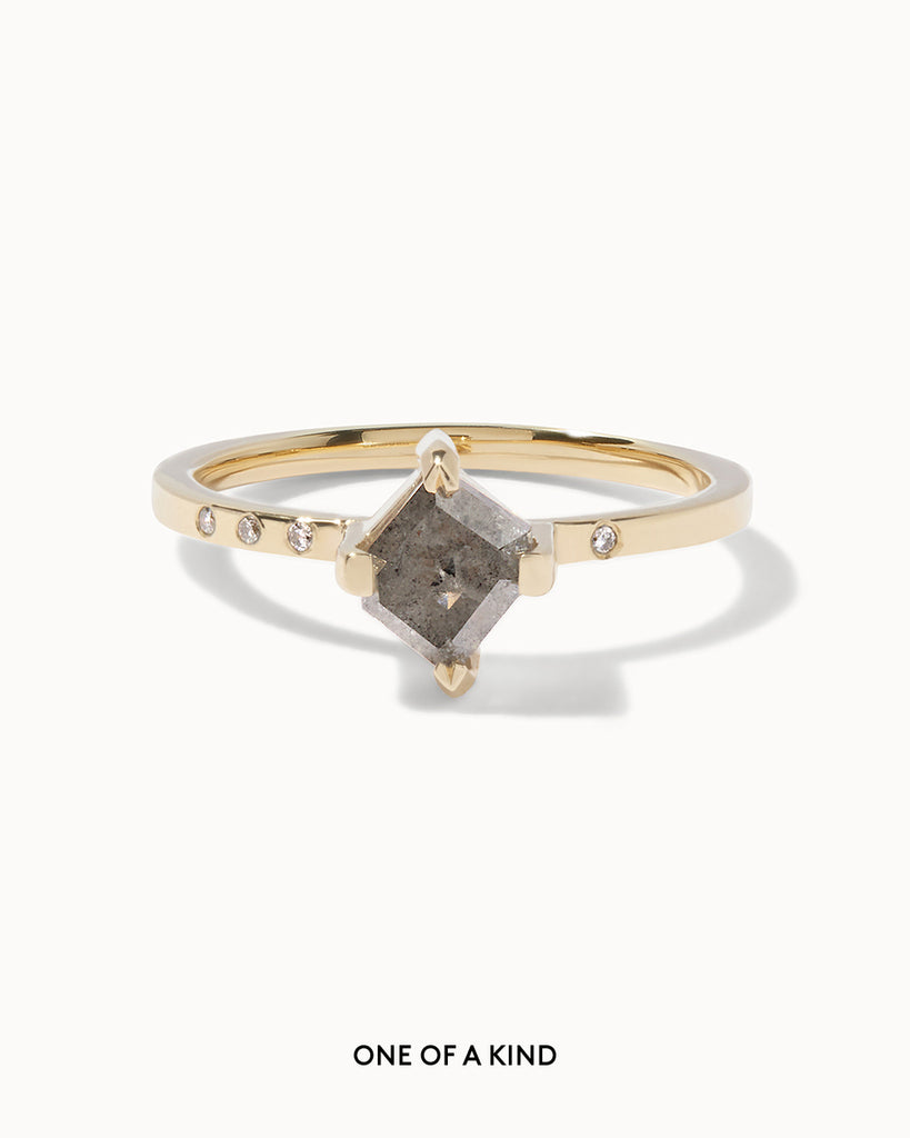 solid gold engagement ring featuring a rectangle cut grey diamond set on a contemporary flat band, studded with bezel set white diamonds handcrafted in London by Maya Magal London