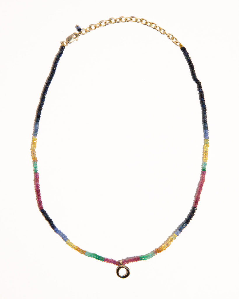 sapphires, emeralds and rubies beaded necklace handstrung on silk thread handcrafted in London with 9ct solid gold organic charm by Maya Magal London