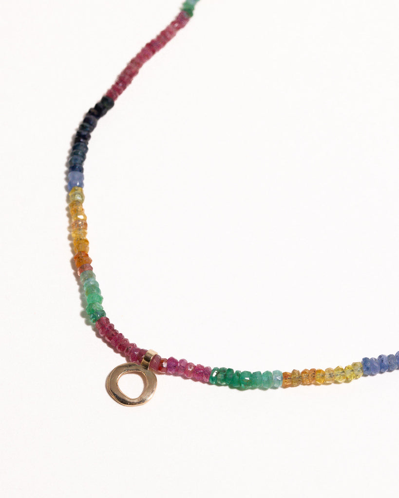 sapphires, emeralds and rubies beaded necklace handstrung on silk thread handcrafted in London with 9ct solid gold organic charm by Maya Magal London