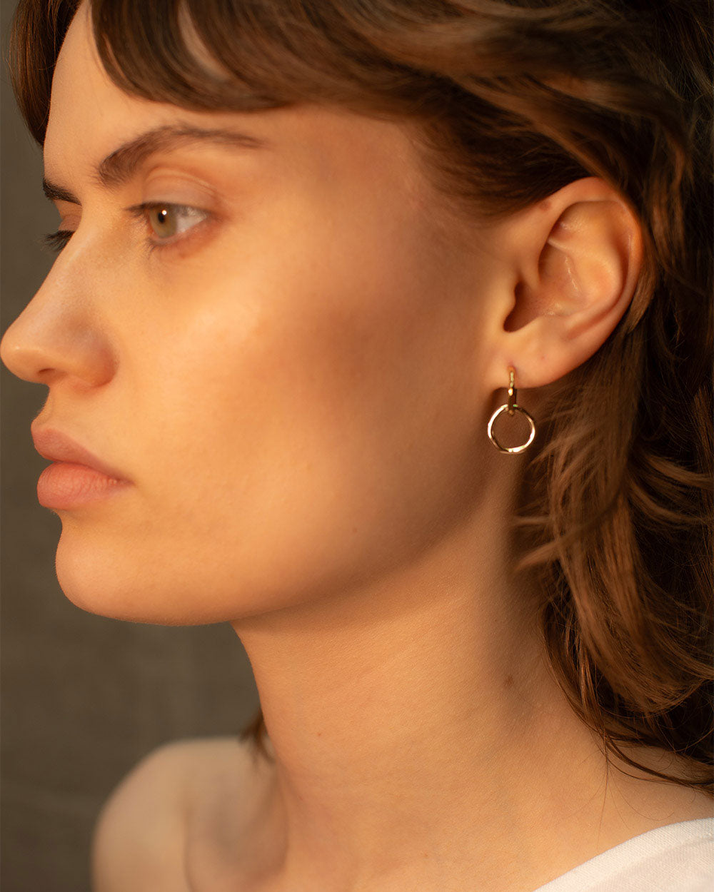 Side view of model wearing 18ct gold plated interlinked hoop earrings.