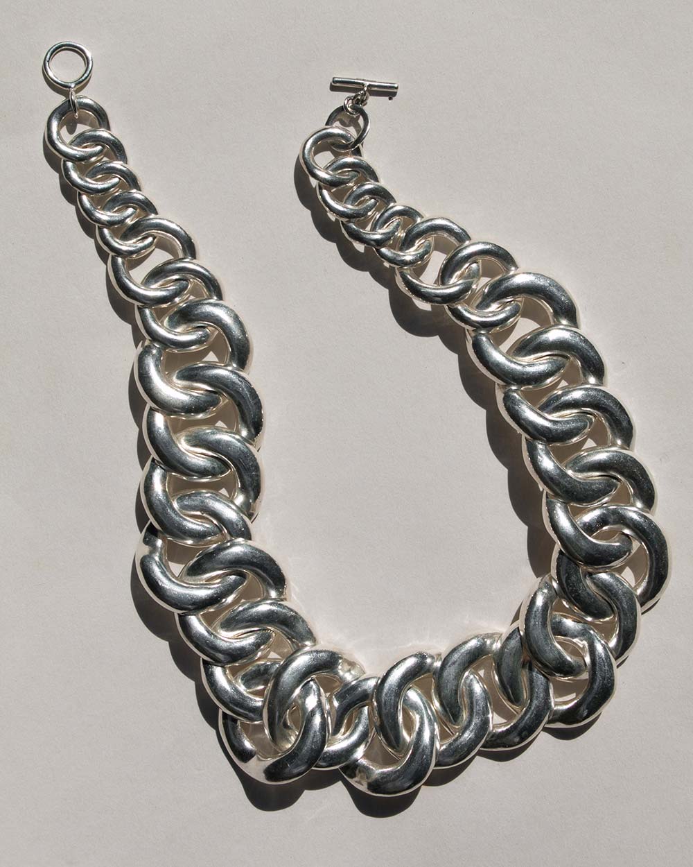 Statement chain link necklace with a t bar closure on a white background. 