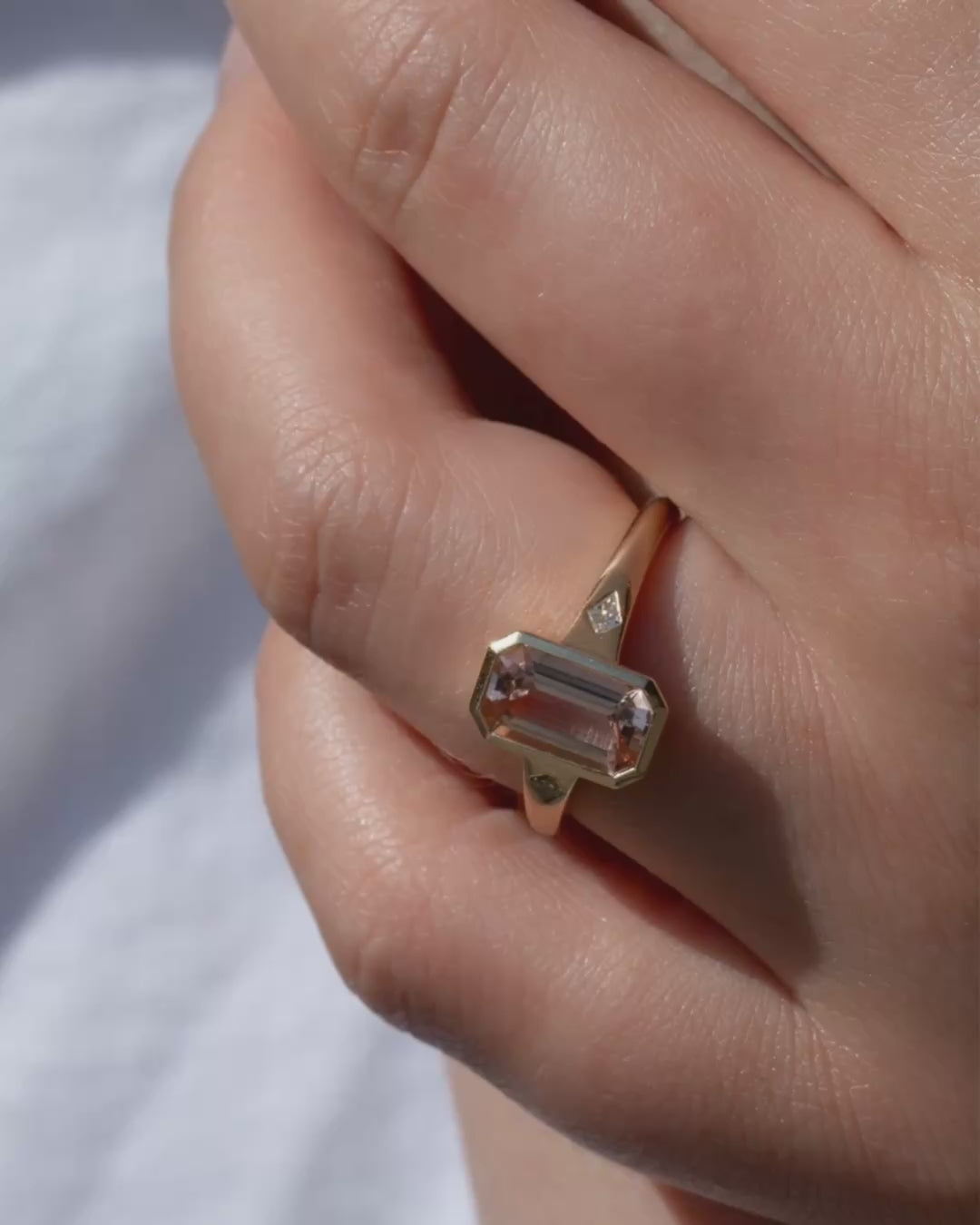 Video of model wearing 9ct solid gold and 1.44ct emerald-cut Brazilian tourmaline. delicate tones of blush and soft rose. Framed by two kite-cut diamonds, the elongated silhouette feels both contemporary and timeless, allowing the natural beauty of the stone to shine through.