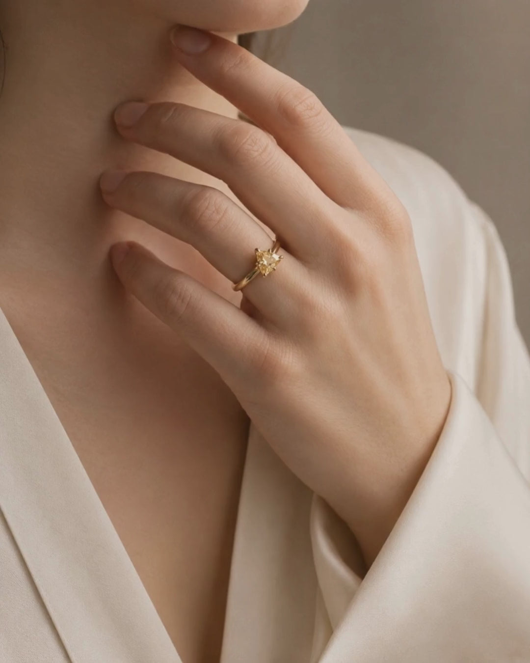 Video of model wearing 9ct solid gold and 0.86ct trillion-cut Brazilian topaz ring. Ring has a warm, subtle colour and unusual triangular form. Held in a talon claw setting, the stone is balanced by a refined knife-edge band. 
