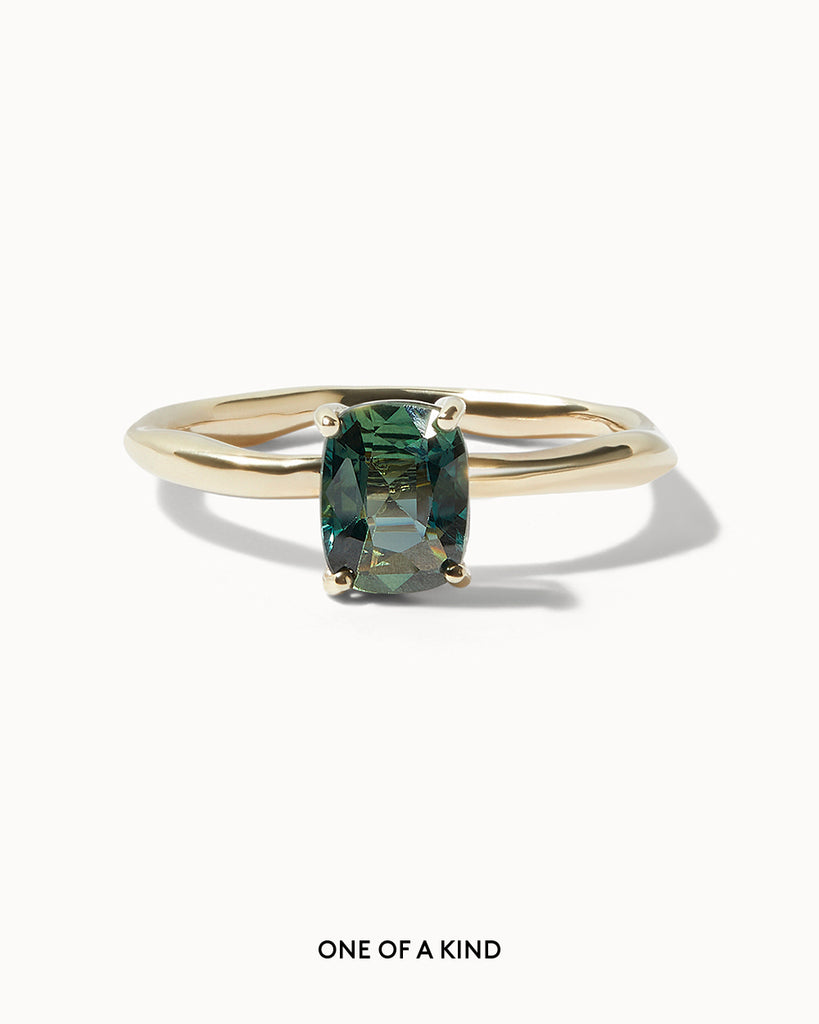 Solid gold solitaire engagement ring featuring a cushion cut teal sapphire set on an organic band handcrafted in London by Maya Magal London